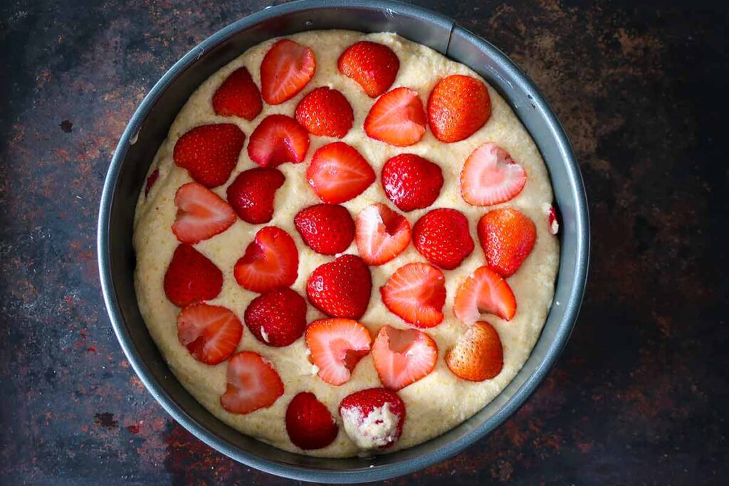 cake batter layered with strawberries in a springform pan