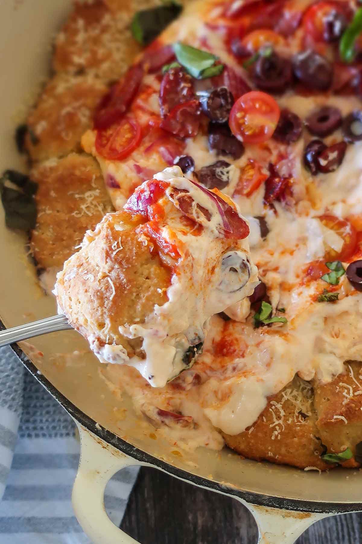 gluten free pizza dip with roll on a spoon over a skillet