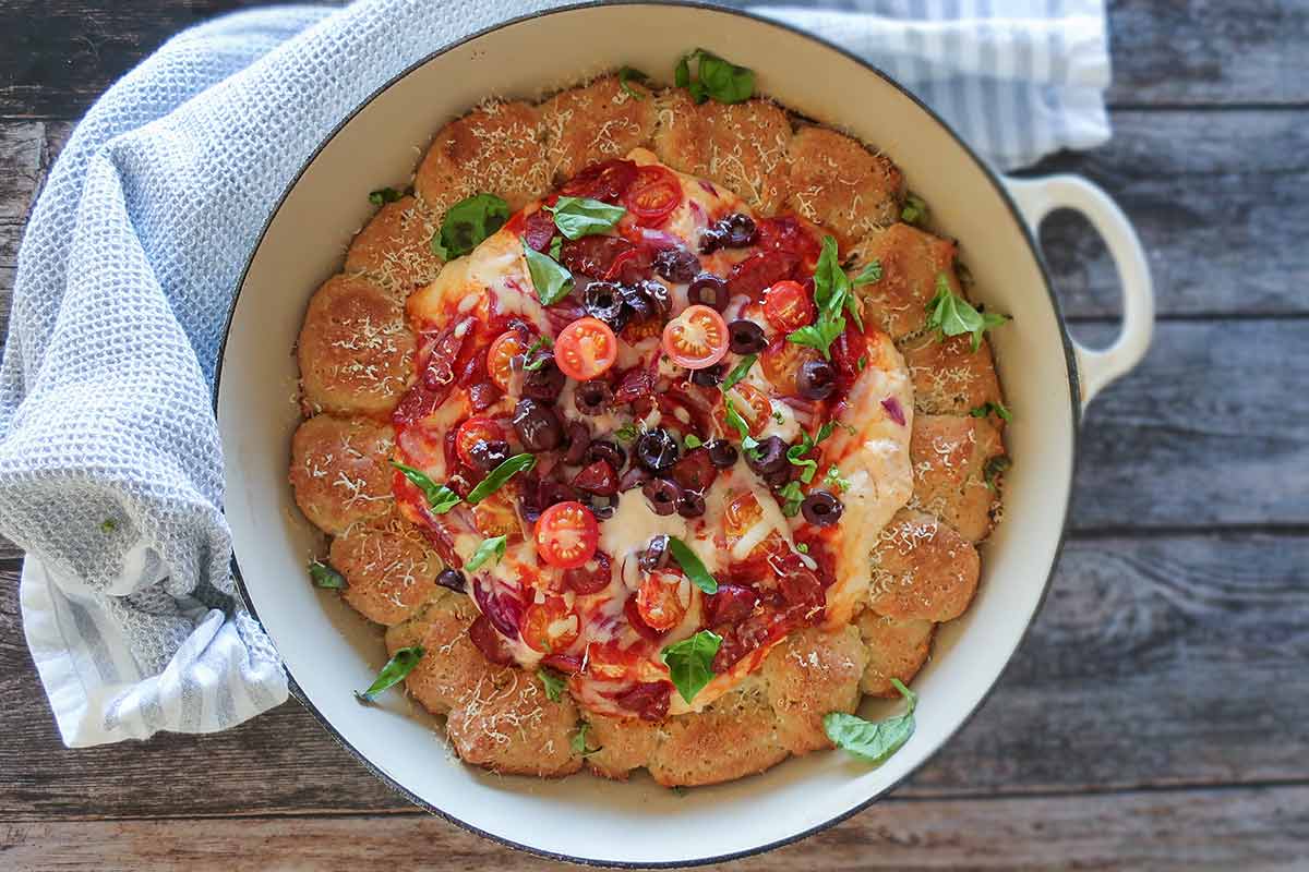 overview of baked pizza dip with rolls in a skillet