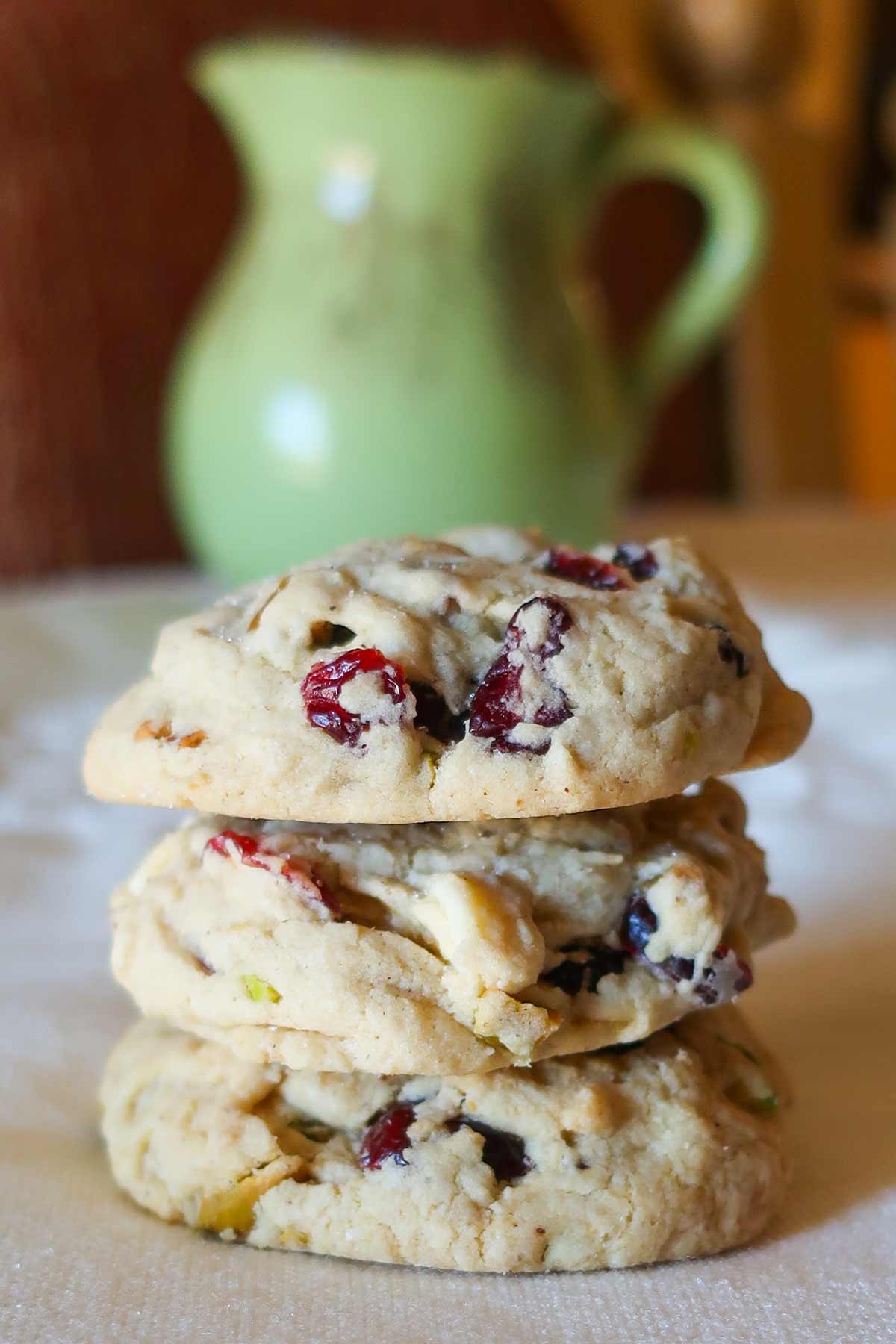 three baked cranberry pistachio cookies and a milk jug