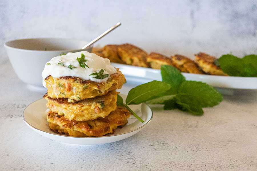 3 salmon burger patties on a plate topped with yogurt