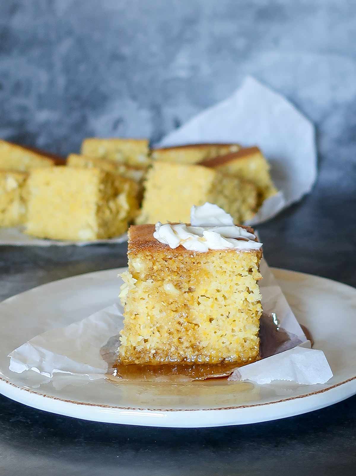 a slice of Caribbean cornbread on a plate topped with honey and butter