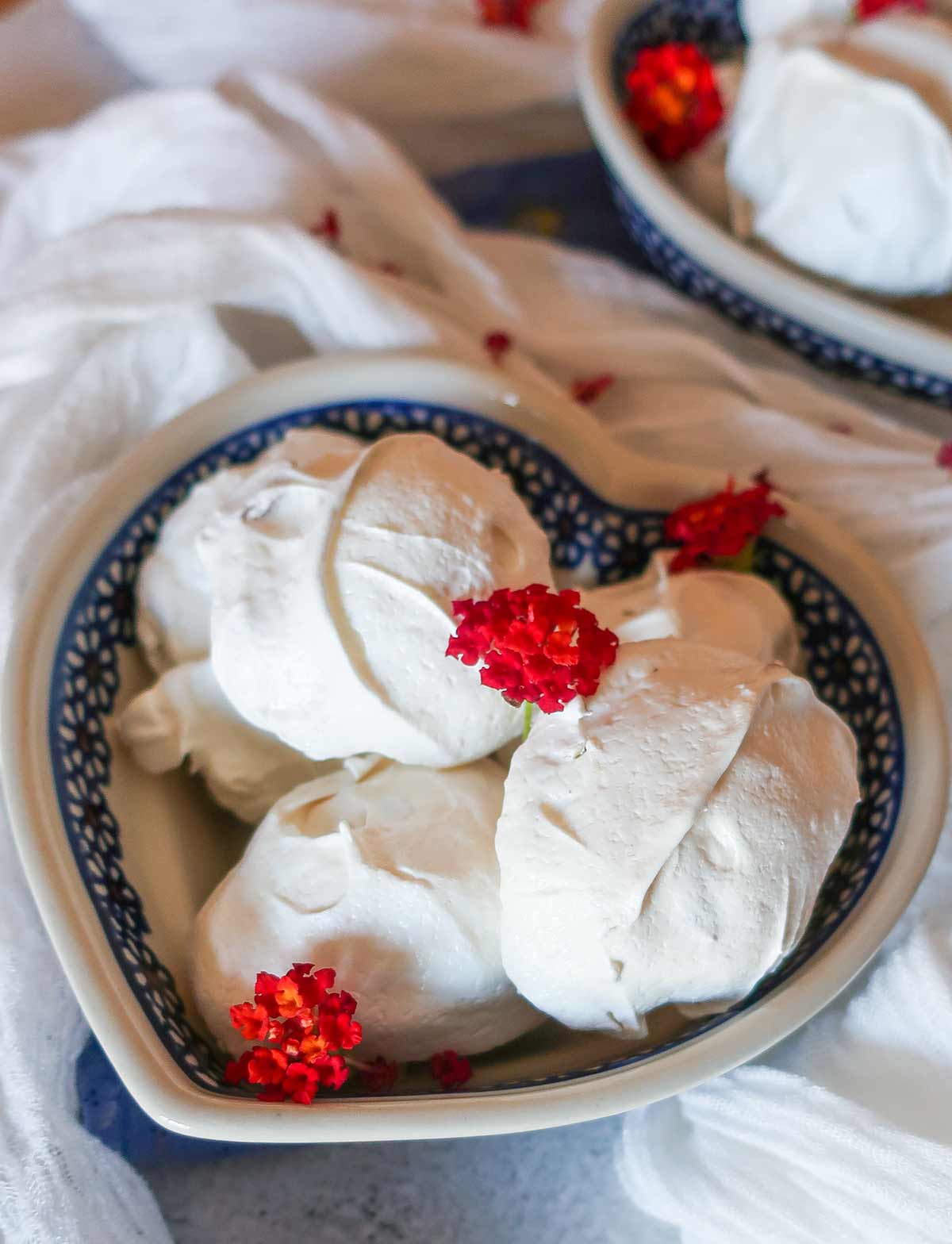 CLOSE UP OF MERINGUE COOKIES TOPPED WITH FLOWERS