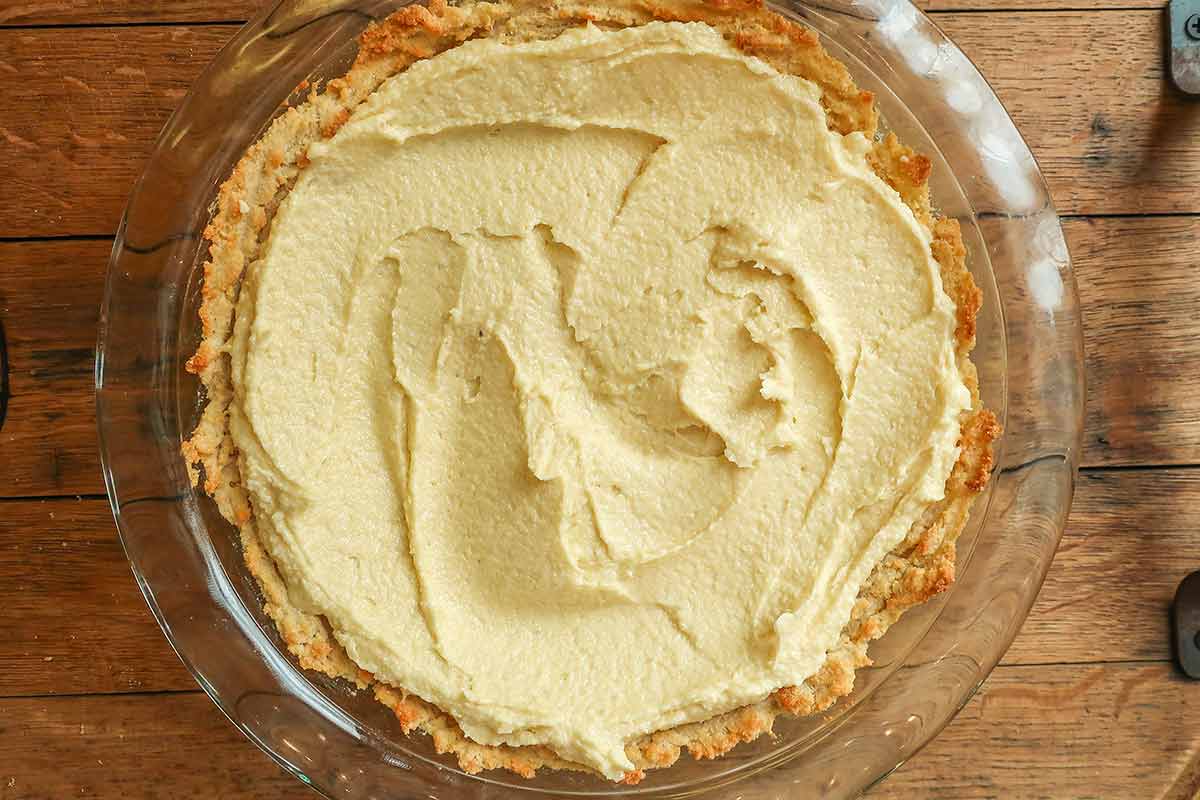 cookie crust topped with frangipane in a pie dish before baking