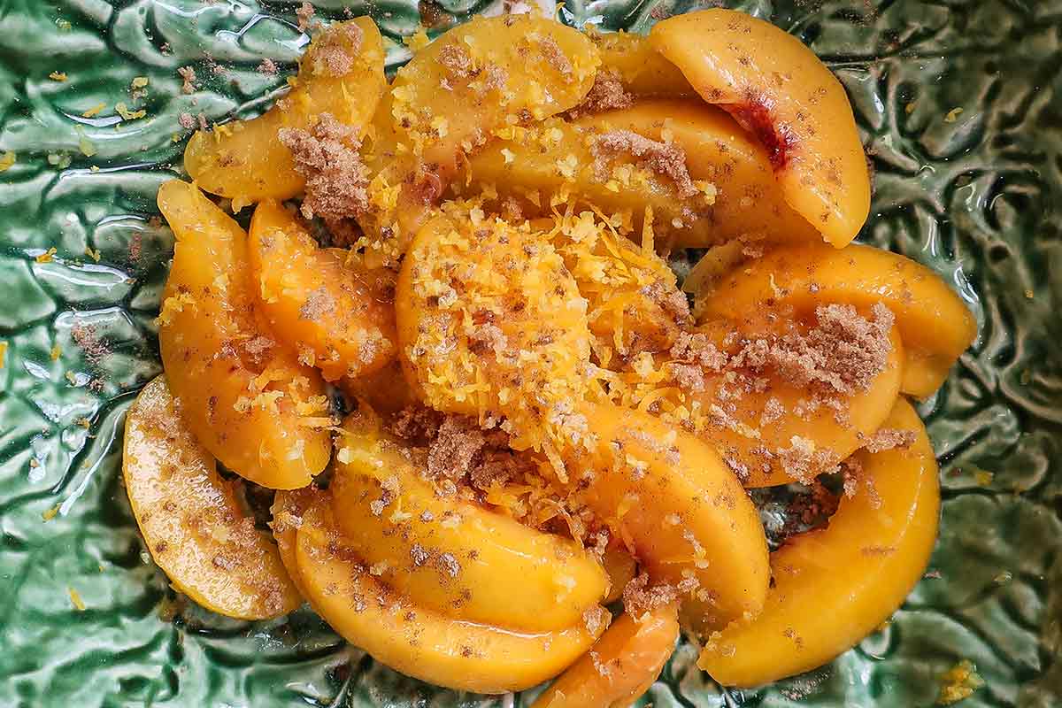 peach slices with lemon zest and cardamom in a bowl