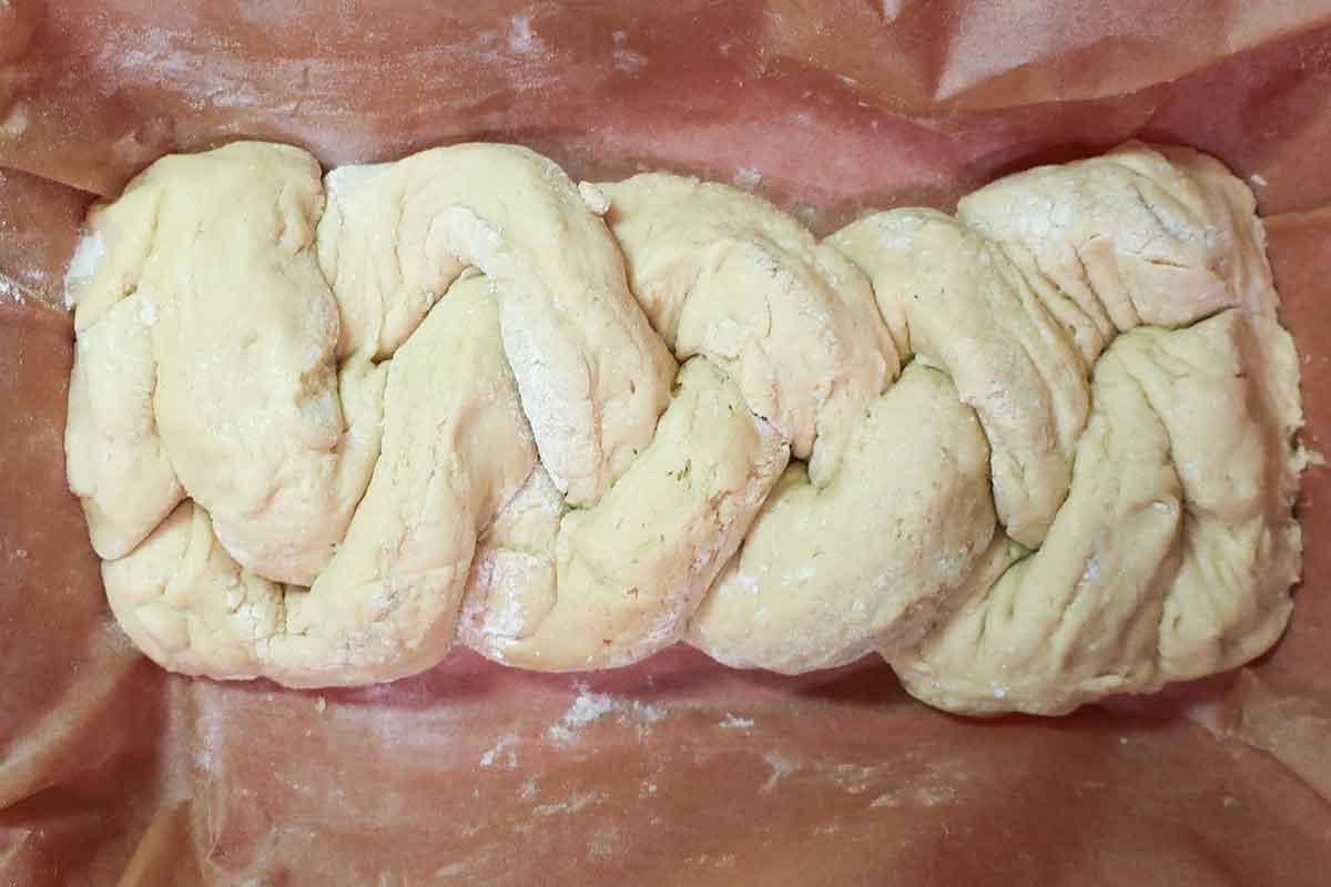 braided challah in a loaf pan before baking