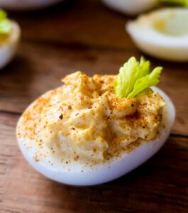 classic devilled egg with celery and paprika garnish