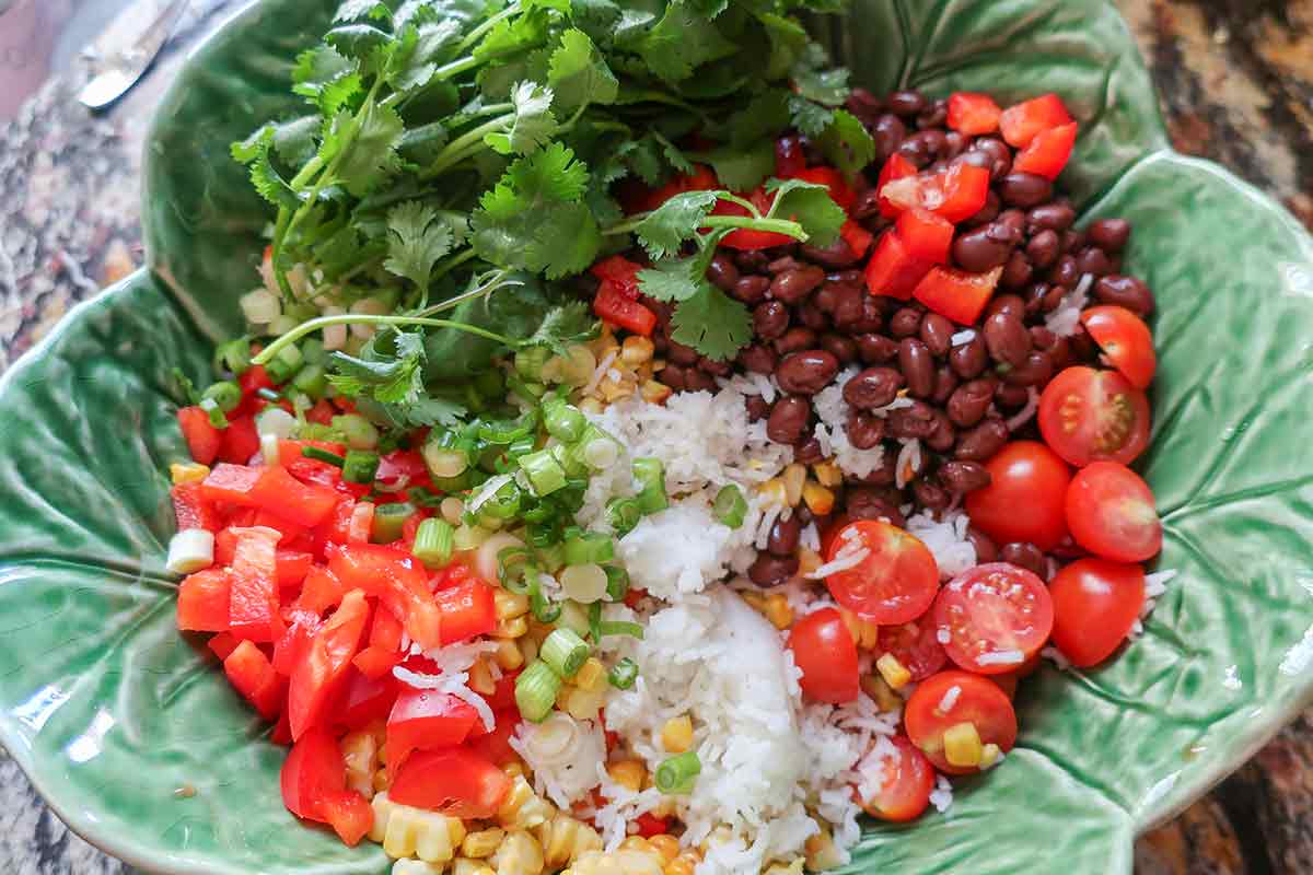 rice, tomatoes, black beans, bell pepper, green onions, corn and cilantro in a bowl