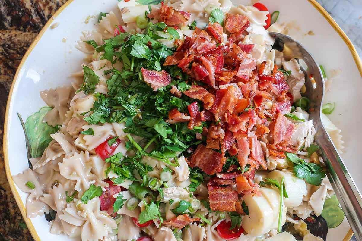 buttermilk chicken pasta salad topped with bacon and lime wedges
