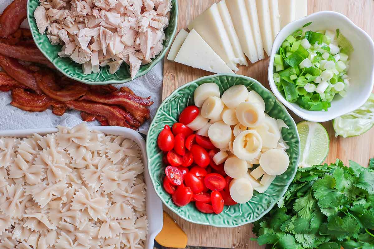 ingredients for pasta salad, chicken, pasta, tomatoes, hearts of palm, cilantro, green onions, cheese
