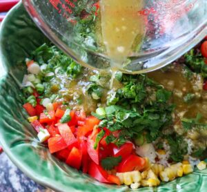 pouring lime cumin vinaigrettte into rice salad. 32 gluten free salad recipes