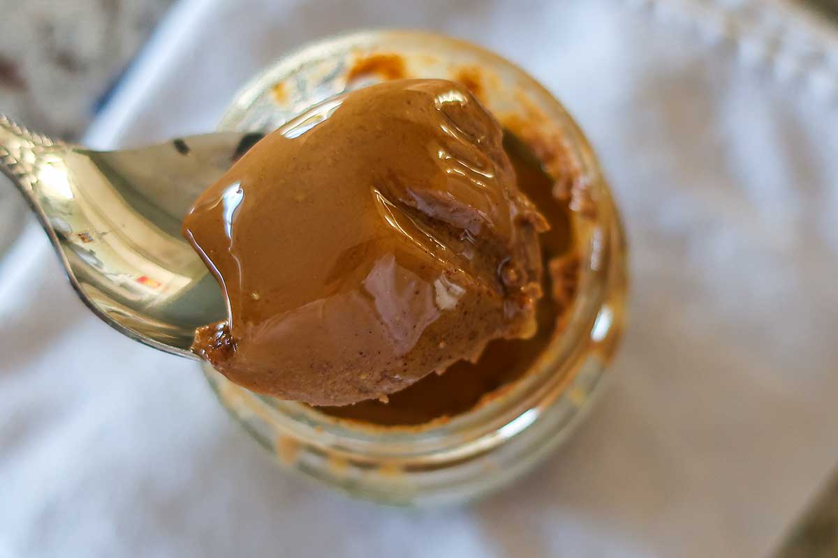 ALMOND BUTTER ON A SPOON FROM A JAR
