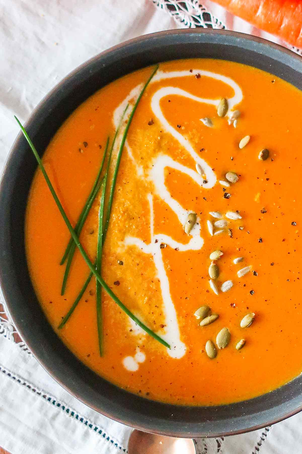 vegan Thai carrot soup in a bowl topped with seeds
