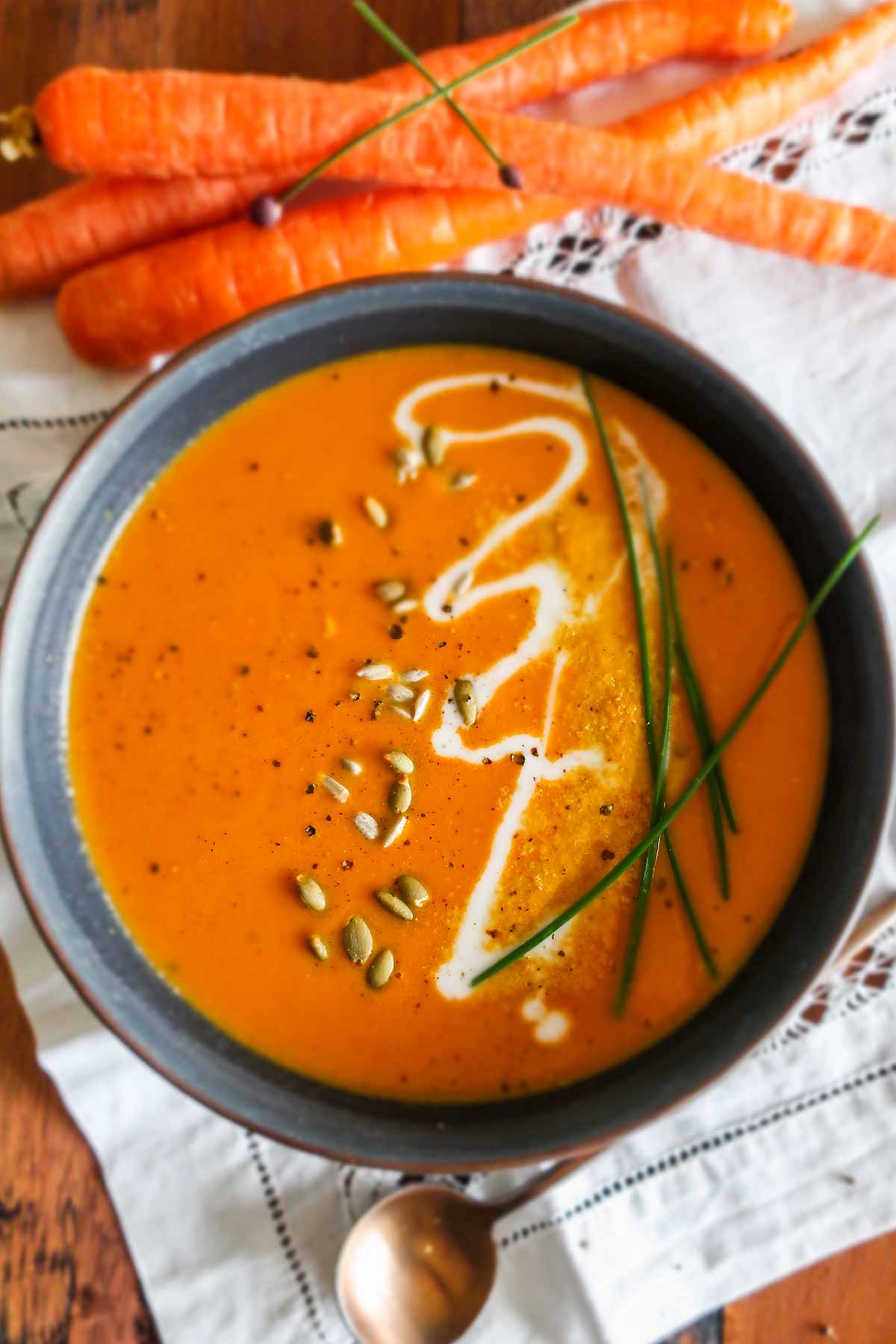 thai carrot soup garnished with seeds, chives and a drizzle of coconut cream