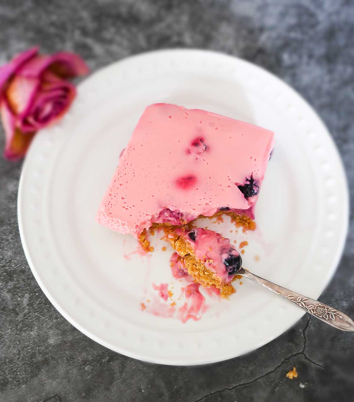 slice of berry cream square on a plate with a fork