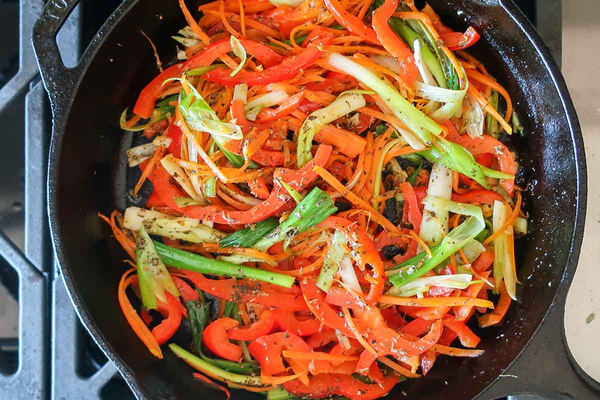 thinly sliced veggies cooked in a cast iron skillet