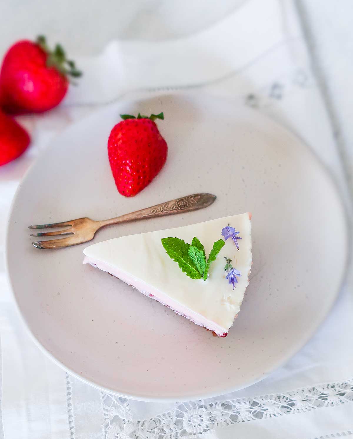 slice of cheesecake with fresh strawberries on a plate