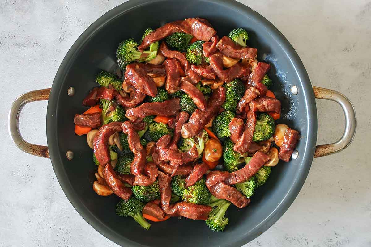 beef and broccoli with sauce in a skillet before cooking