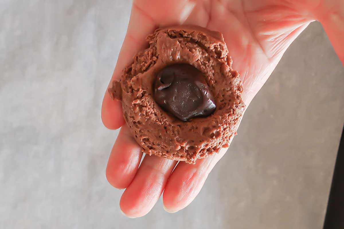 chocolate ball in the center of cookie dough in palm of a hand