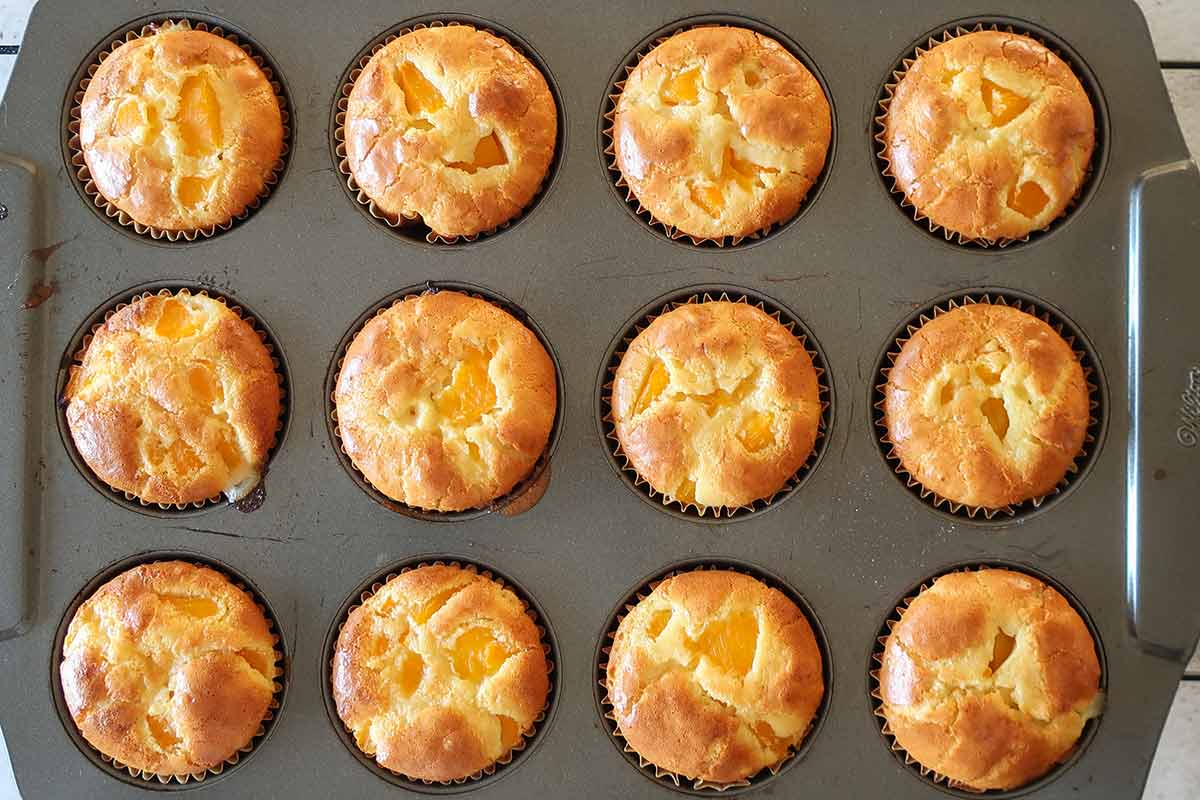 baked peach pudding muffins in a muffin pan