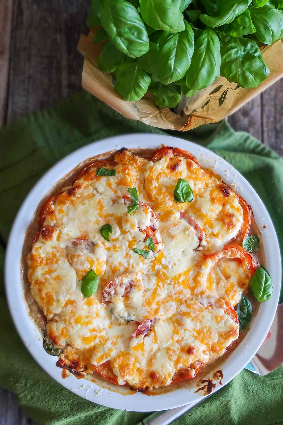 overview of whole gluten free tomato pie with basil plant on the side