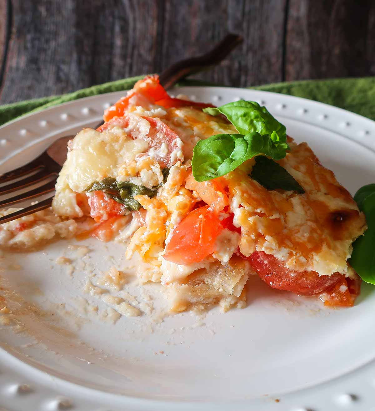 slice of half eaten tomato pie on a plate with a fork