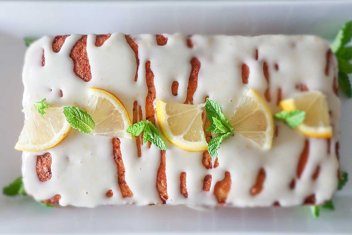 showing top of zucchini lemon rice flour loaf with lemon glaze and lemon slices