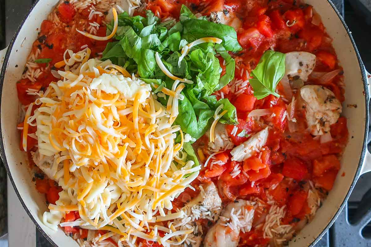 shredded cheese, tomatoes, basil, rice and chicken in a skillet before baking