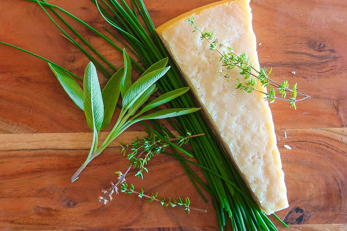 fresh herbs and a piece of parmesan on a cutting board