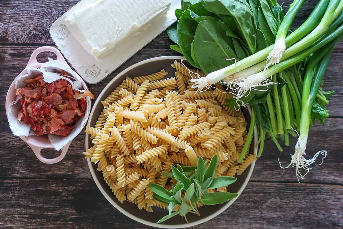 ingredients for bacon and spinach pasta, gluten free pasta, cooked bacon, cream cheese, green onions spinach herbs