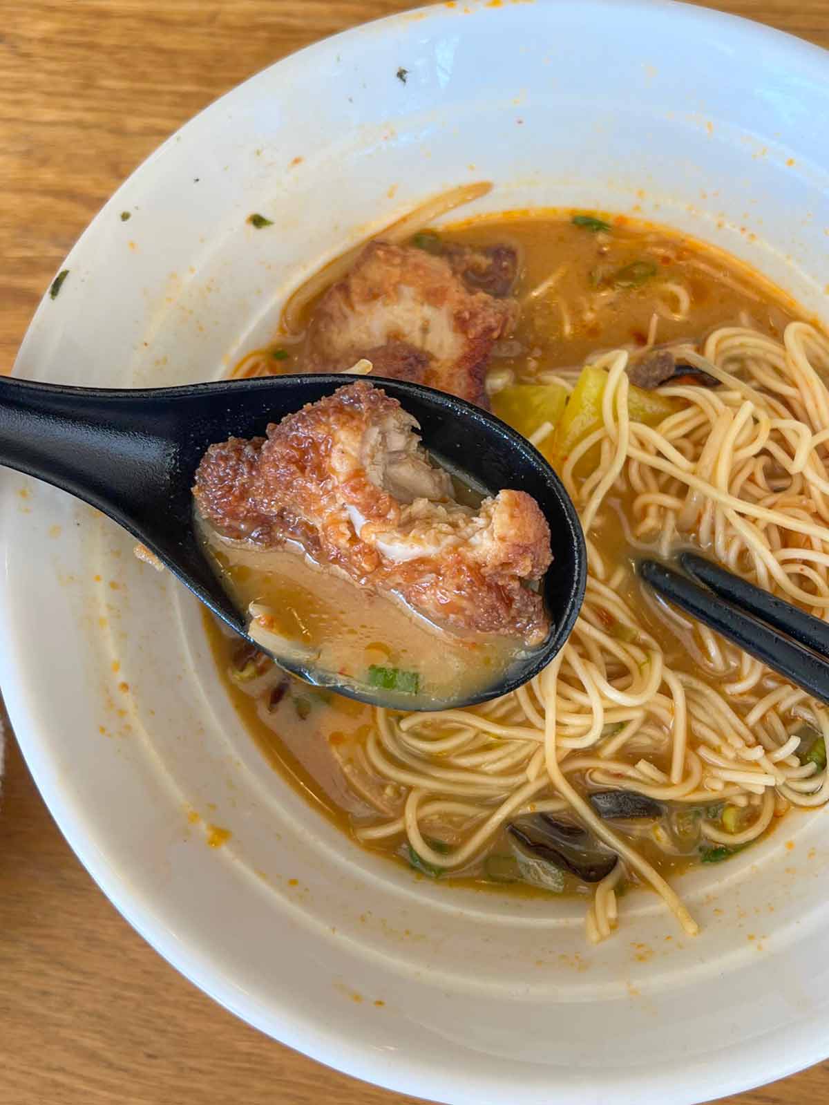 chicken Karaage on a spoon over bowl of ramen soup