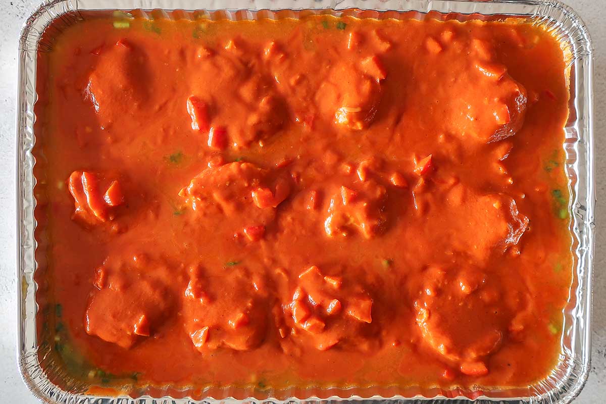 rice topped with meatballs and sauce in a baking dish before baking