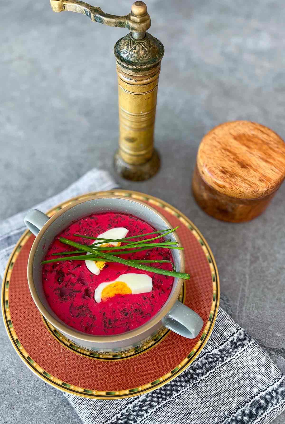 chlodnik in a bowl with pepper grinder and sliced egg