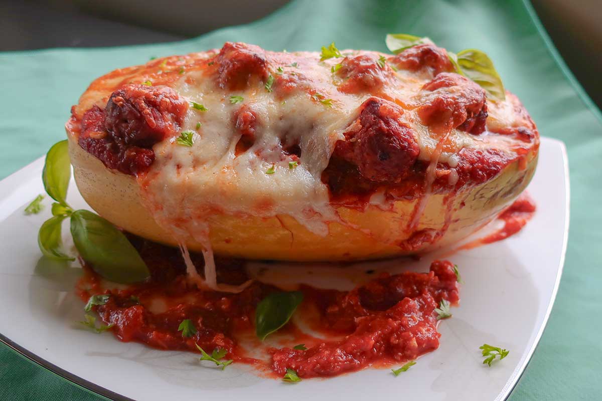 spaghetti squash half filled with meatballs in marinara sauce topped with melted cheese. Perfect GF recipe for fall