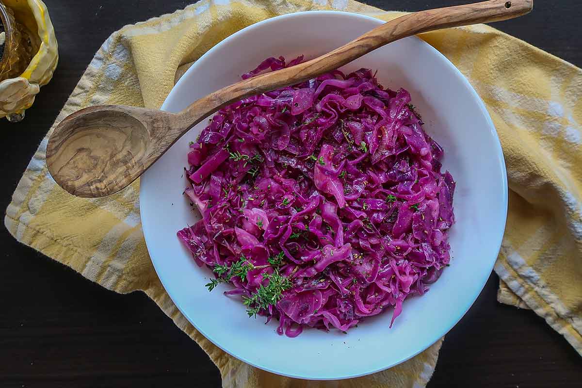 braised red cabbage in a bowl with a wooden spoon