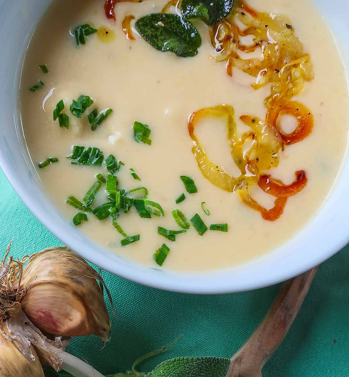 close up of cheesy cauliflower soup in a bowl with toppings