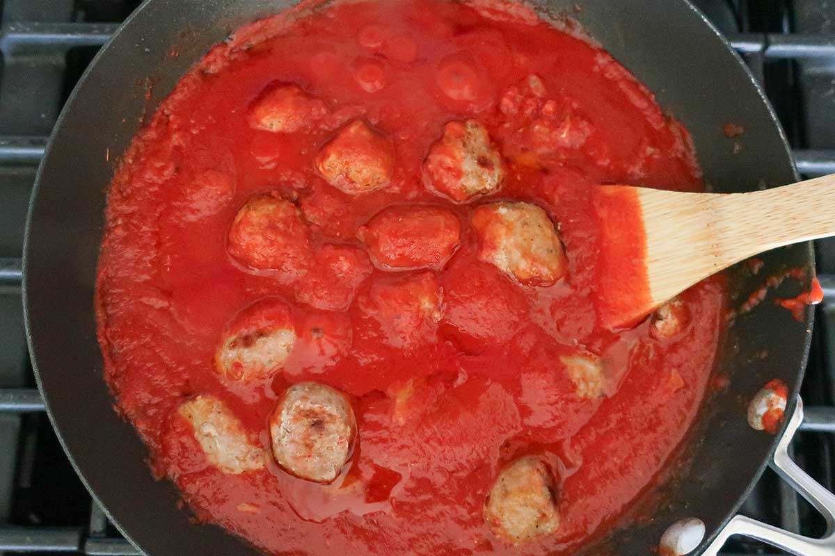 meatballs simmering with marinara sauce in a skillet