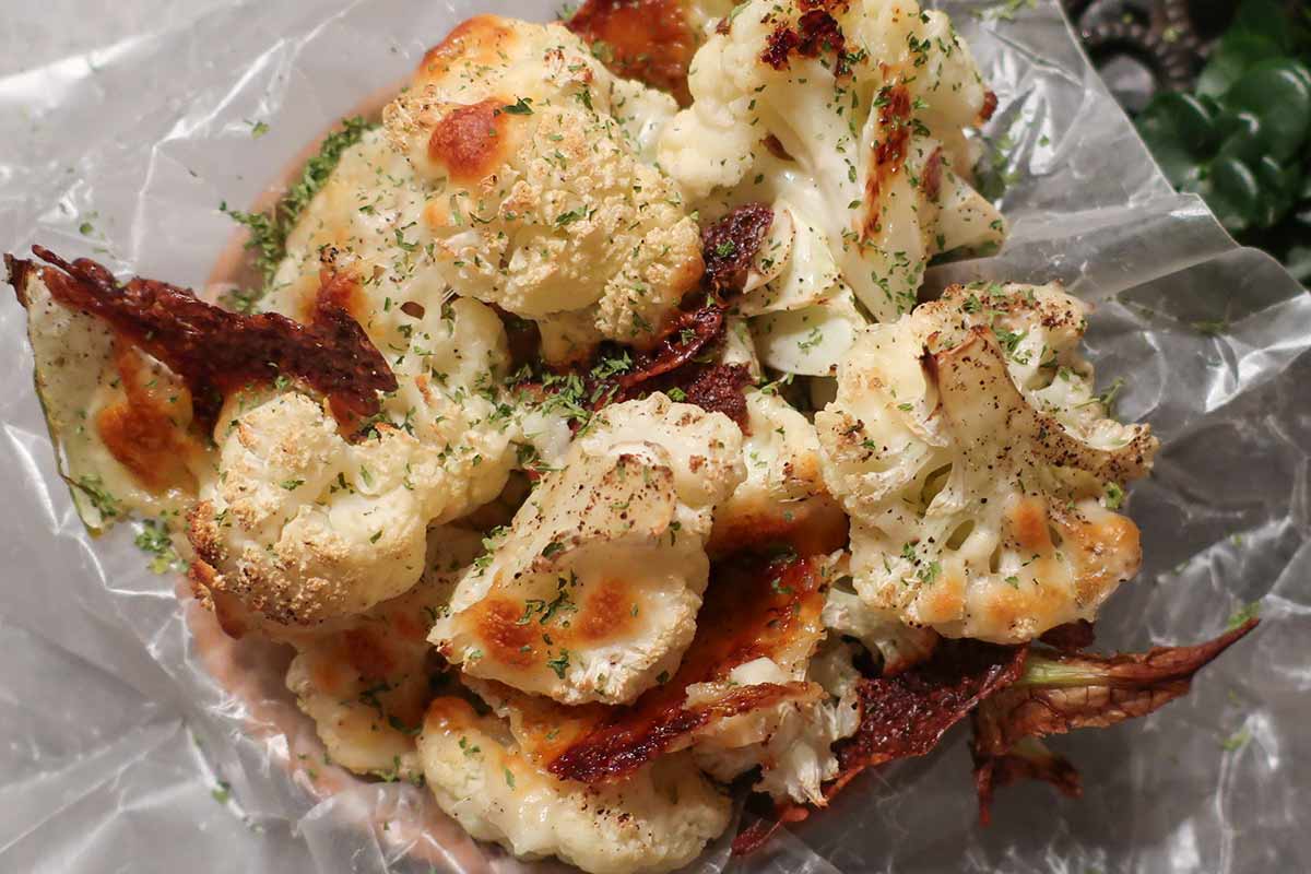 golden brown pieces of cauliflower with melted cheese on parchment