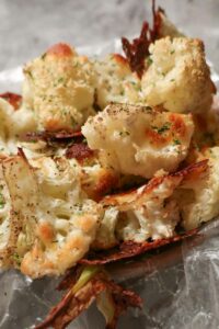 pieces of cheesy roasted cauliflower bites in a bowl