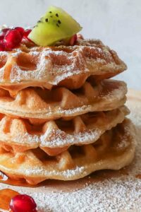 gluten-free-mothers-day-brunch-ideas. 4 stacked gluten free waffles topped with fruit maple syrup and powdered sugar