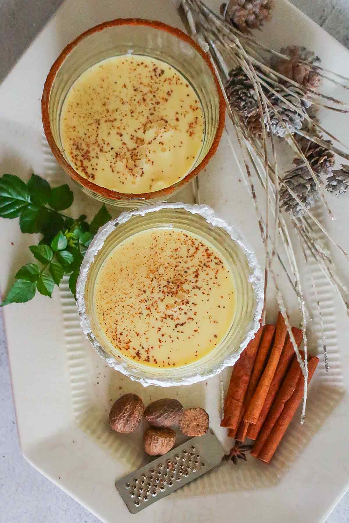 A top view of two glasses of eggnog, with cinnamon and sugar on the rims