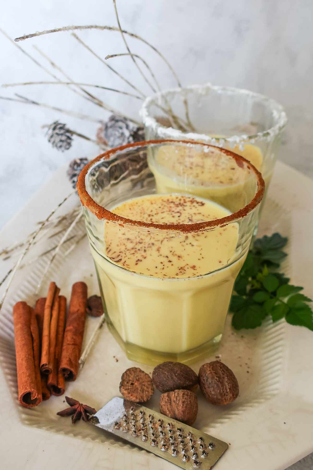 Two glasses of eggnog, rimmed with cinnamon and sugar