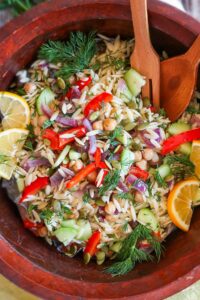 gluten free orzo salad with roasted veggies and seeds in a wooden salad bowl