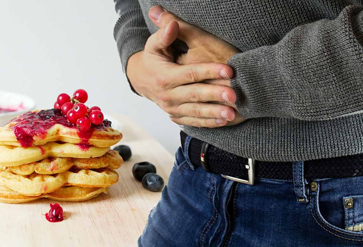 man in pain holding his stomach after eating gluten. Celiac disease myths