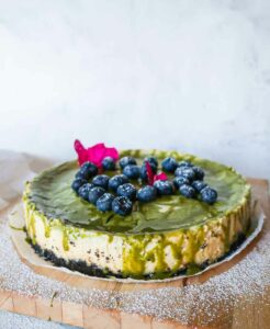 baked matcha cheesecake decorated with matcha glaze and blueberries