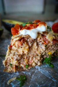 slice of gluten free taco pie topped with sour cream and fresh tomatoes