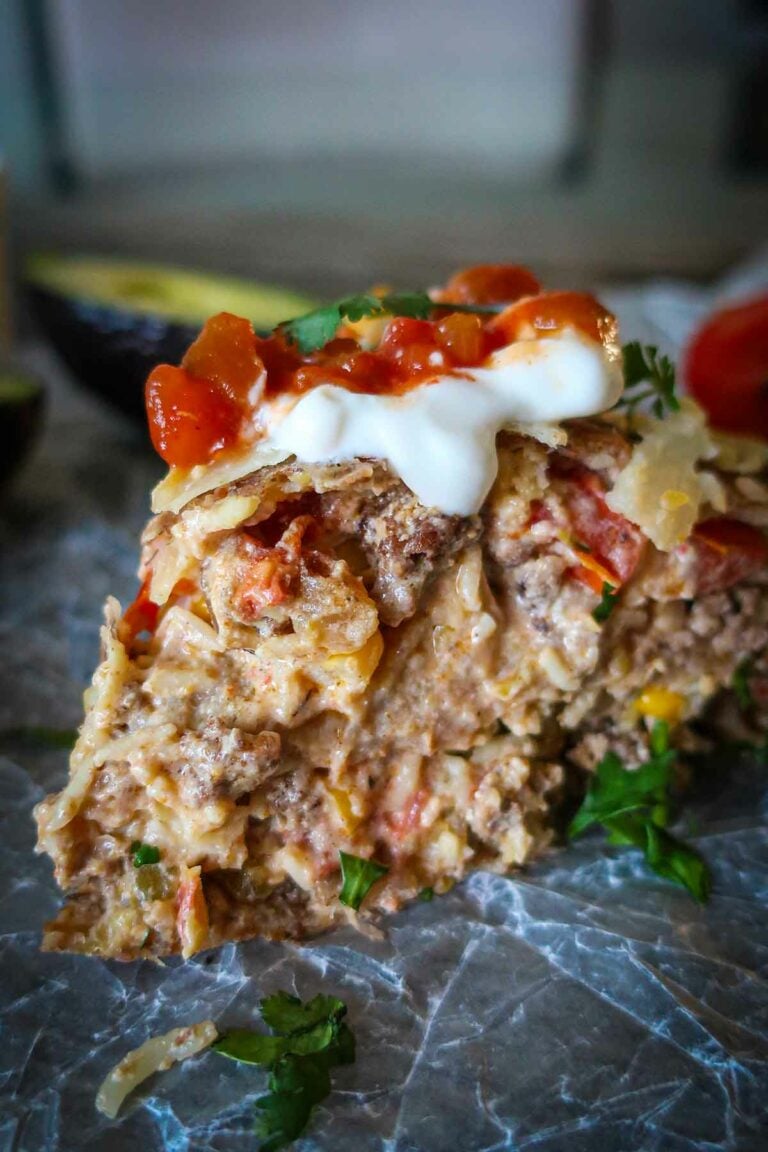 slice of gluten free taco pie topped with sour cream and fresh tomatoes