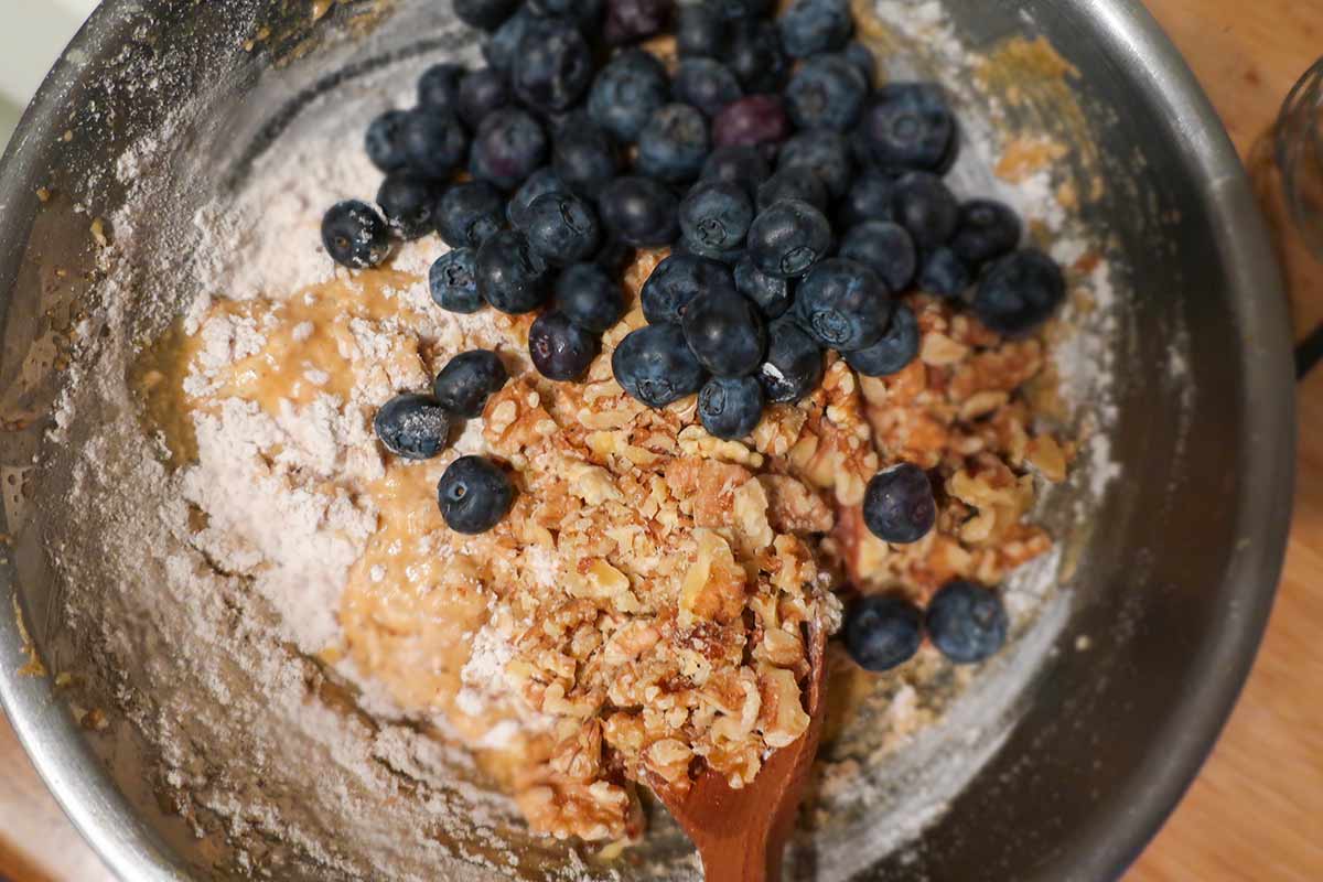 flour, blueberries, walnuts and milk in a mixing bowl