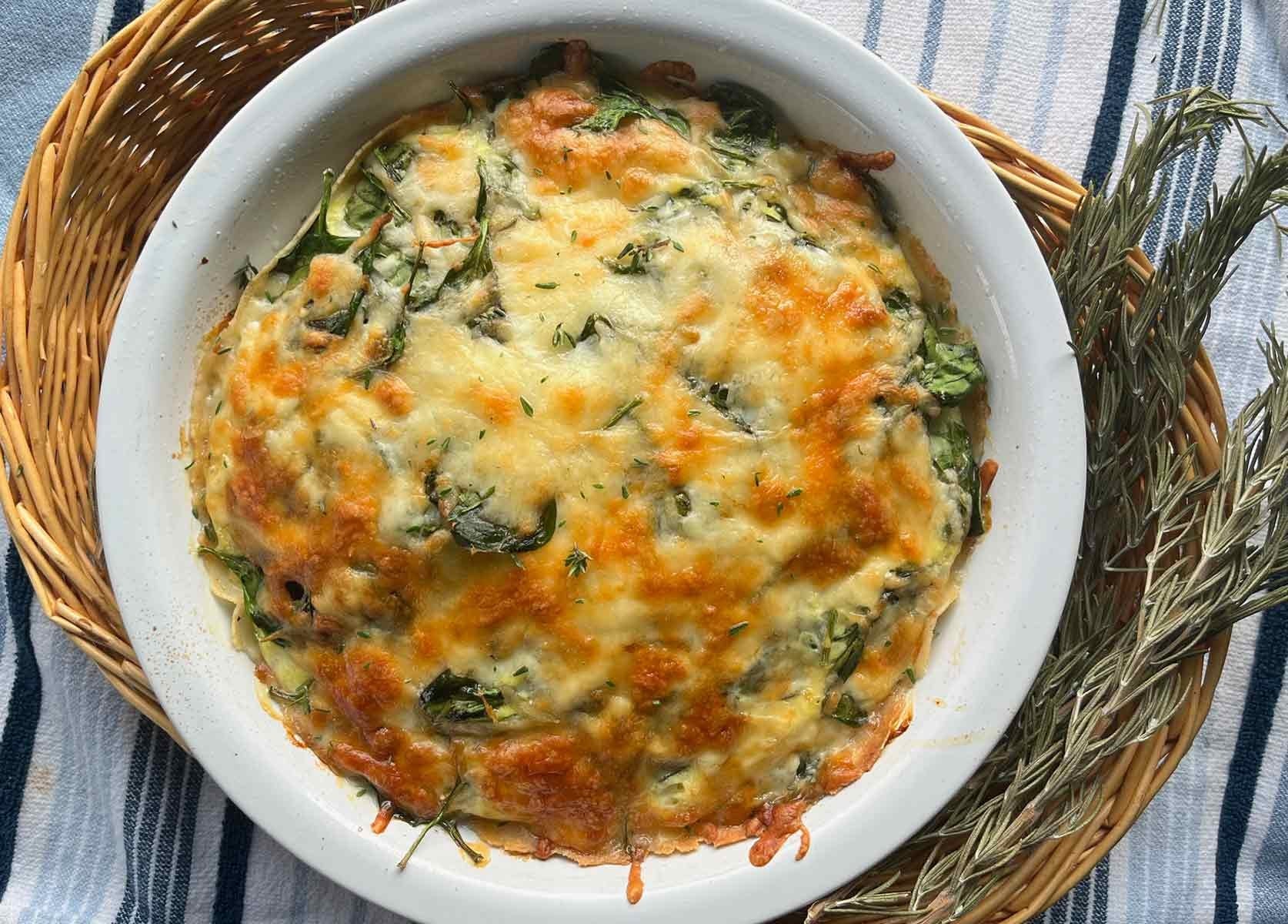 Baked breakfast tortilla quiche with spinach and cheese, served in a pie dish.