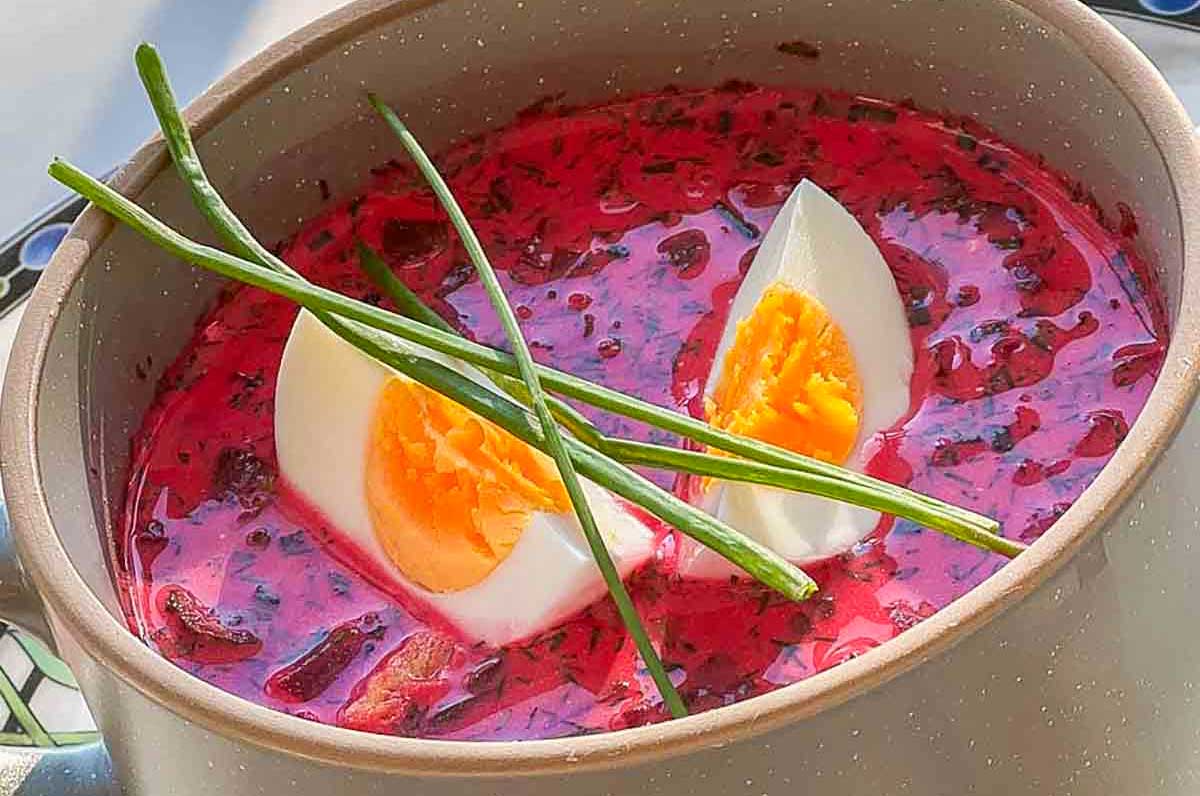 polish borscht in a cup topped with hard boiled egg and chives